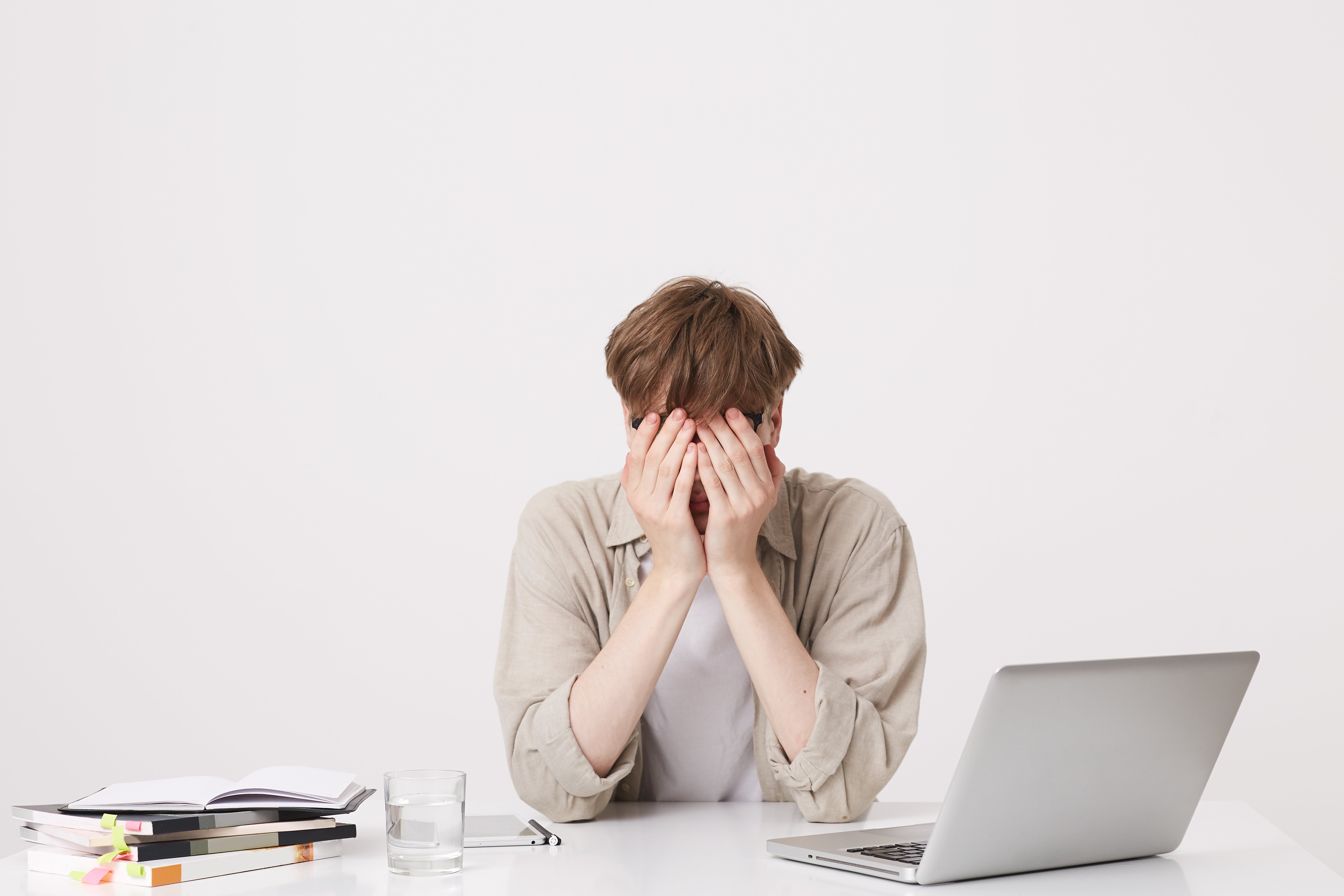 closeup-cheerful-young-male-student-with-braces-wears-beige-shirt-study-using-laptop-computer-notebooks-sitting-table-isolated-white-wall