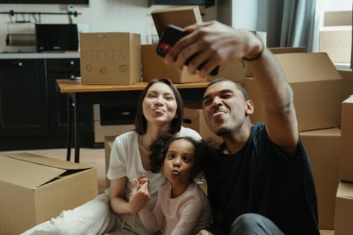 A family takes a selfie surrounded by boxes in their new home 